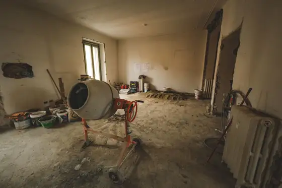 A concrete mixer and buckets on a site in a room under renovation