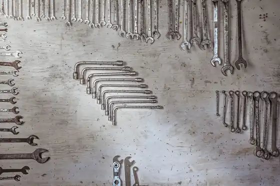 A set of spanners and hex keys laid out on a workshop board
