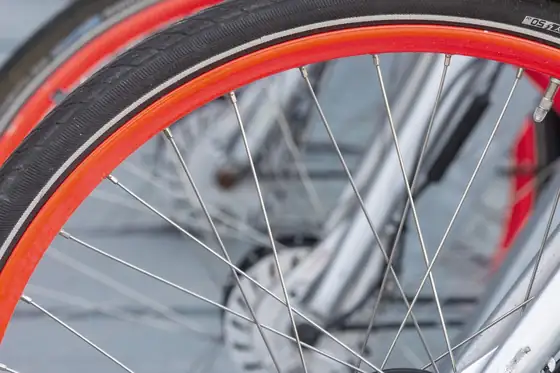 A row of identical bicycle wheels with red rims